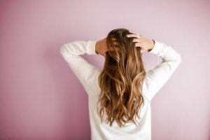 Woman facing wall with hands in her hair